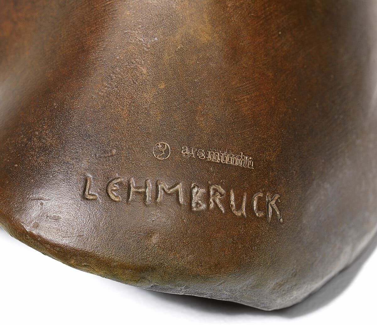 Nahaufnahme einer Bronzeskulptur von Wilhelm Lehmbruck mit der Aufschrift 'LEHMBRUCK' und dem Jahr '1910'. Die Skulptur zeigt wohl einen Gesekten Frauenkopf.