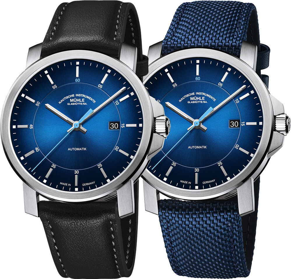 Zwei elegante Automatikuhr-Modelle der ZEIT-Sonderedition »29er Casual« von Mühle-Glashütte: linke Uhr mit schwarzem Lederarmband, rechte mit nautikblauem Canvas-Armband. Beide zeigen ein blaues Zifferblatt mit Strahlenschliff, Edelstahlgehäuse, Datumsanzeige und schlichten Indexen.