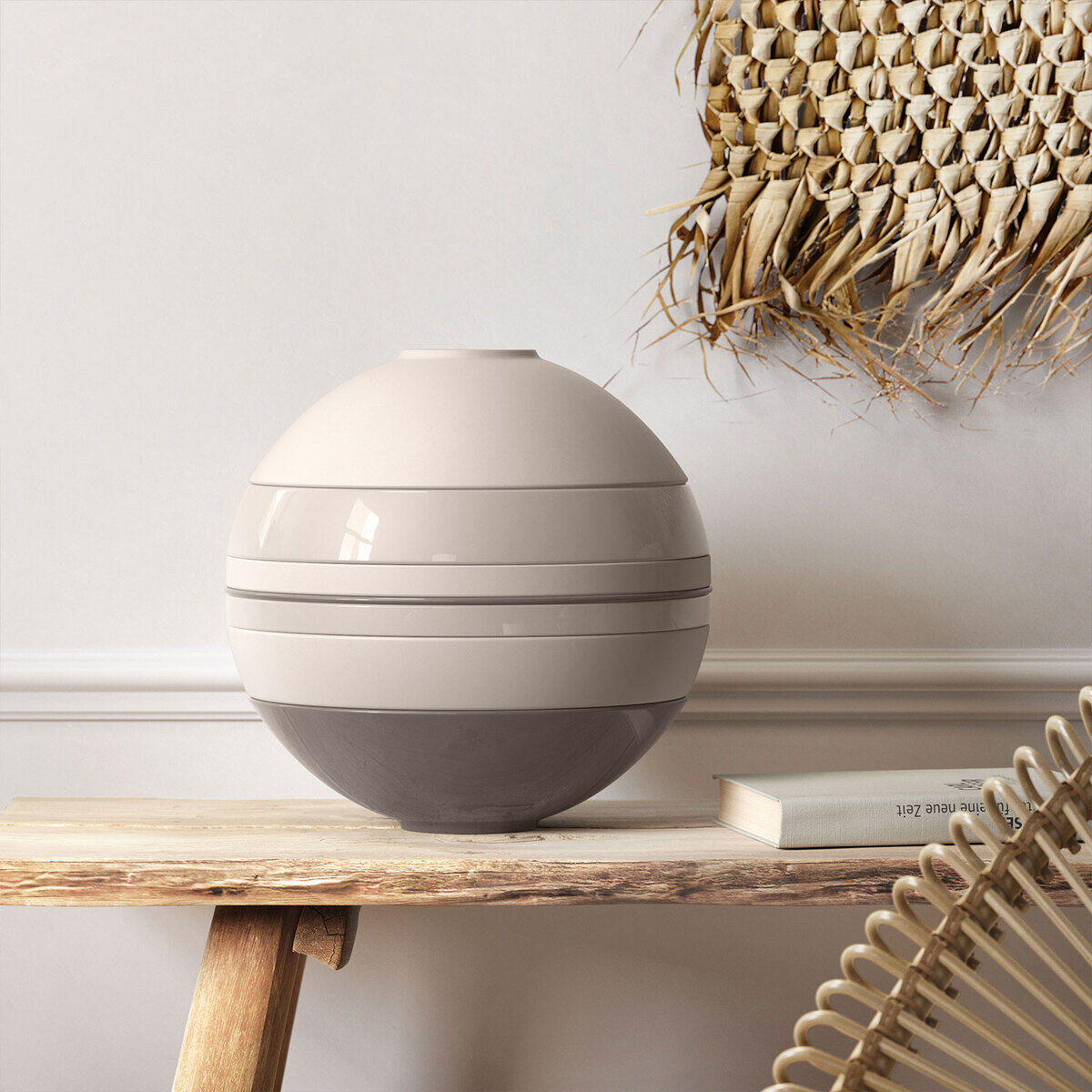 Das Bild zeigt ein modernes Geschirr-Set namens »La Boule«, das aus mehreren runden, ineinander stapelbaren Teilen besteht. Das Set steht auf einem Holztisch vor einer hellen Wand mit einer dekorativen Palme im Hintergrund.
