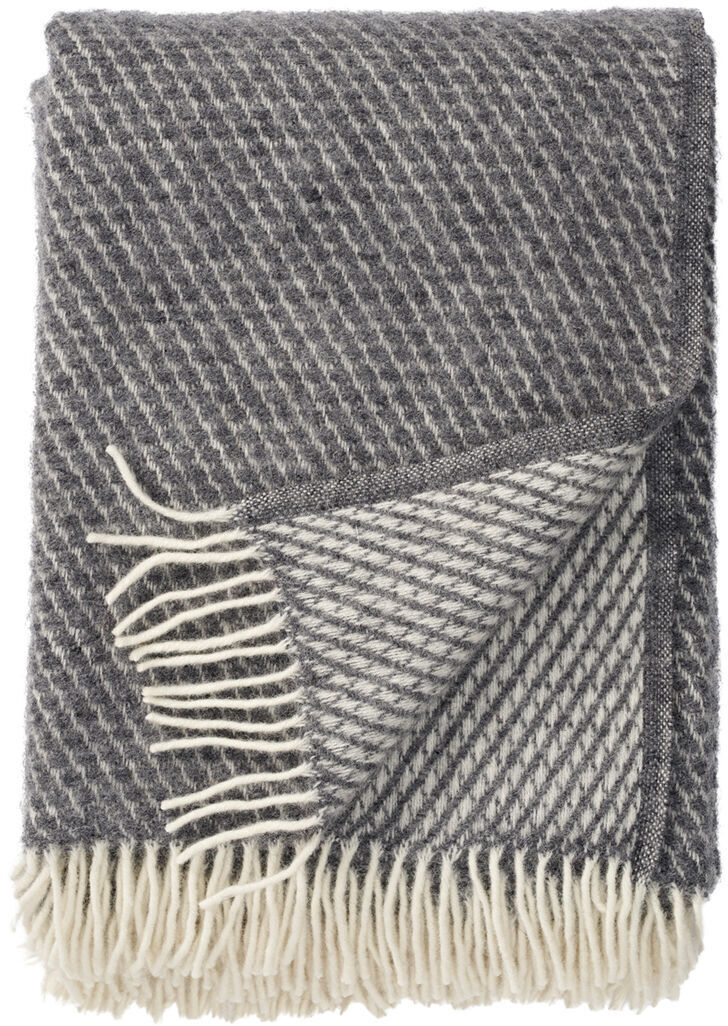 Zusammengefaltete Decke »Velvet« mit grauem und cremefarbenem Fransenmuster. Die Decke ist weich und gemütlich, ideal für Wohnzimmer oder als Sofadecke.