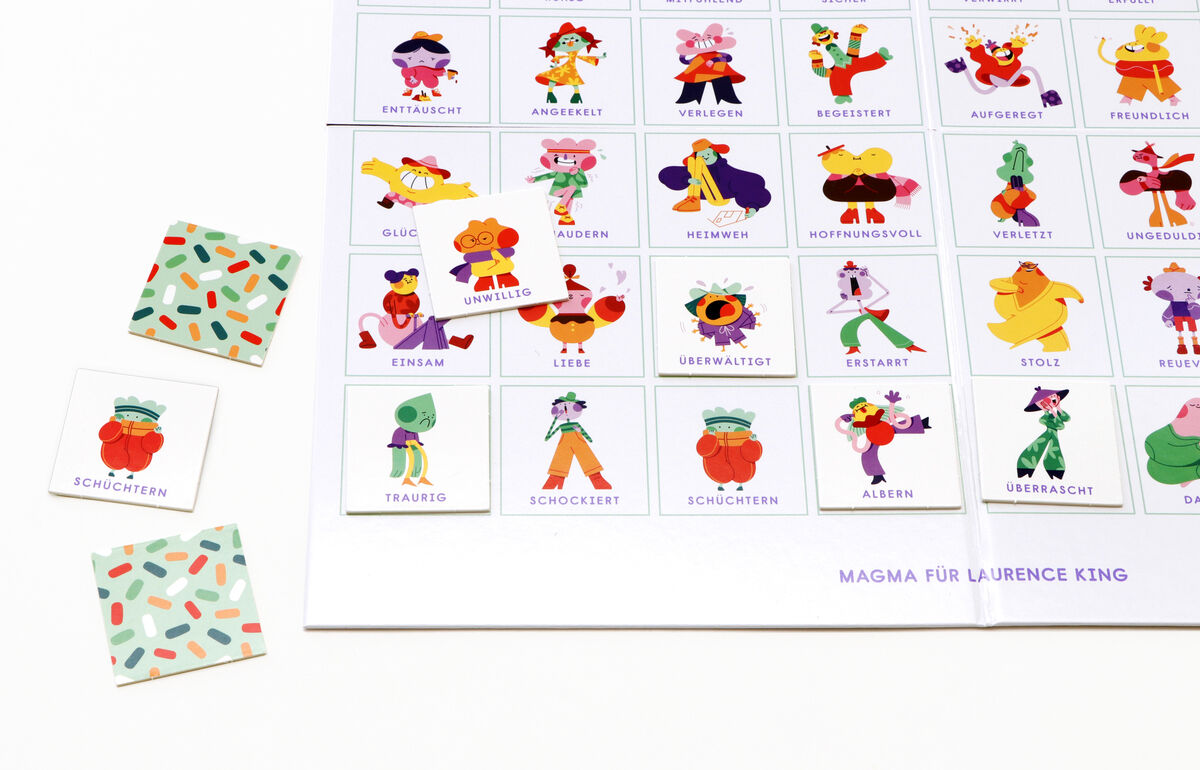 Das Bild zeigt das Brettspiel 'Bingo der Emotionen' mit verschiedenen bunten Illustrationen, die verschiedene menschliche Emotionen darstellen. Es gibt auch zwei quadratische Karten, die separate Emotionsbilder enthalten.