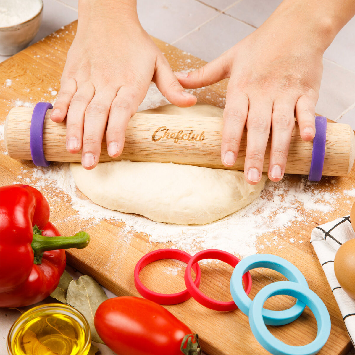 Kinder backen Teig mit Kochutensilien aus Holz, farbigen Ringen und Gemüse wie Paprika in der Küche.