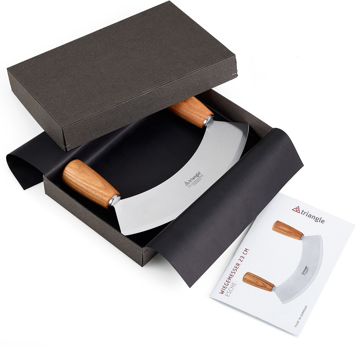 Das Wiegemesser »Soul« von triangle liegt elegant in einer schwarzen Geschenkbox. Die Klinge ist aus glänzendem Edelstahl, die beiden Griffe aus geölter Kernesche-Holz. Daneben liegt eine Produktkarte mit Abbildung und Details zum Messer. Moderner, stilvoller Auftritt.