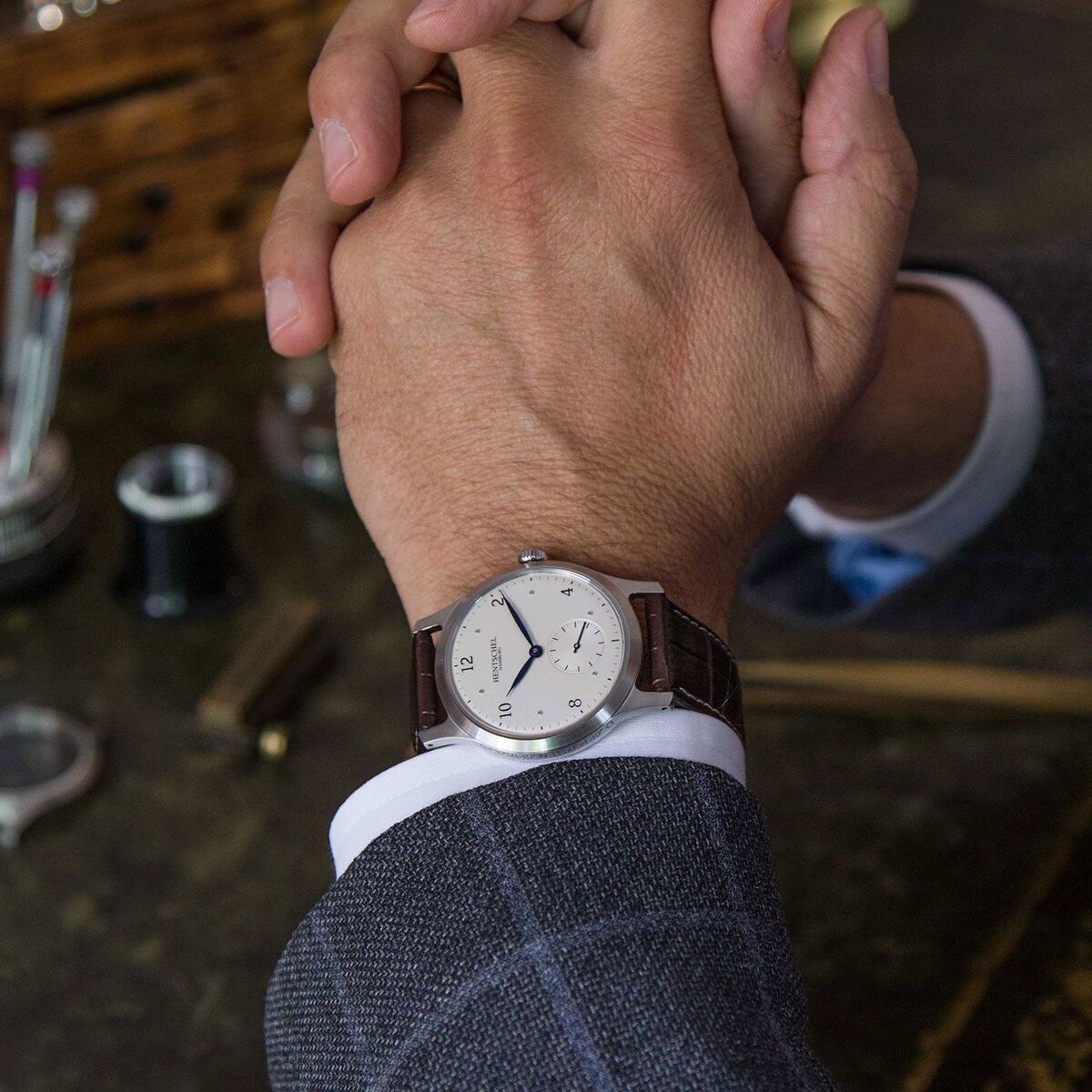 Nahaufnahme einer männlichen Hand, die eine Armbanduhr ZEIT-Chronometer H2 Hamburg mit braunem Lederarmband trägt. Die Uhr hat ein silbernes Zifferblatt und silberne Zeiger.