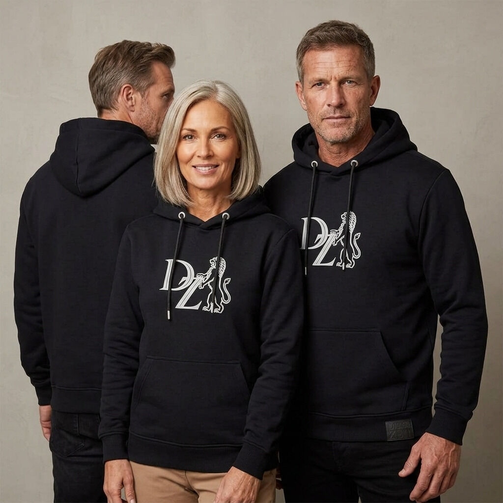 Drei Erwachsene präsentieren den schwarzen »ZEIT« Hoodie aus der ZEIT-Kollektion. Der Hoodie zeigt einen auffälligen, grauen Schaumprint mit ZEIT-Löwenlogo auf der Brust, hat schwarze Kordeln, geprägte Ösen und ein kleines Lederlabel am Saum. Der Hintergrund ist hellgrau.