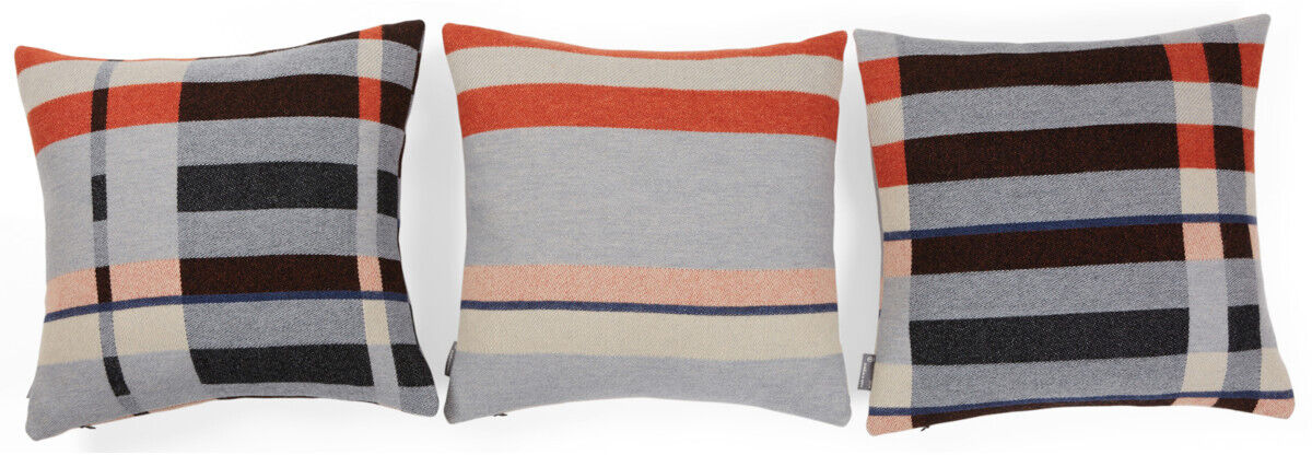 Drei dekorative Kissen mit geometrischen, gestreiften Mustern in den Farben Orange, Grau, Schwarz und Beige. Die Designs sind modern und an das Bauhaus-Stil erinnert.