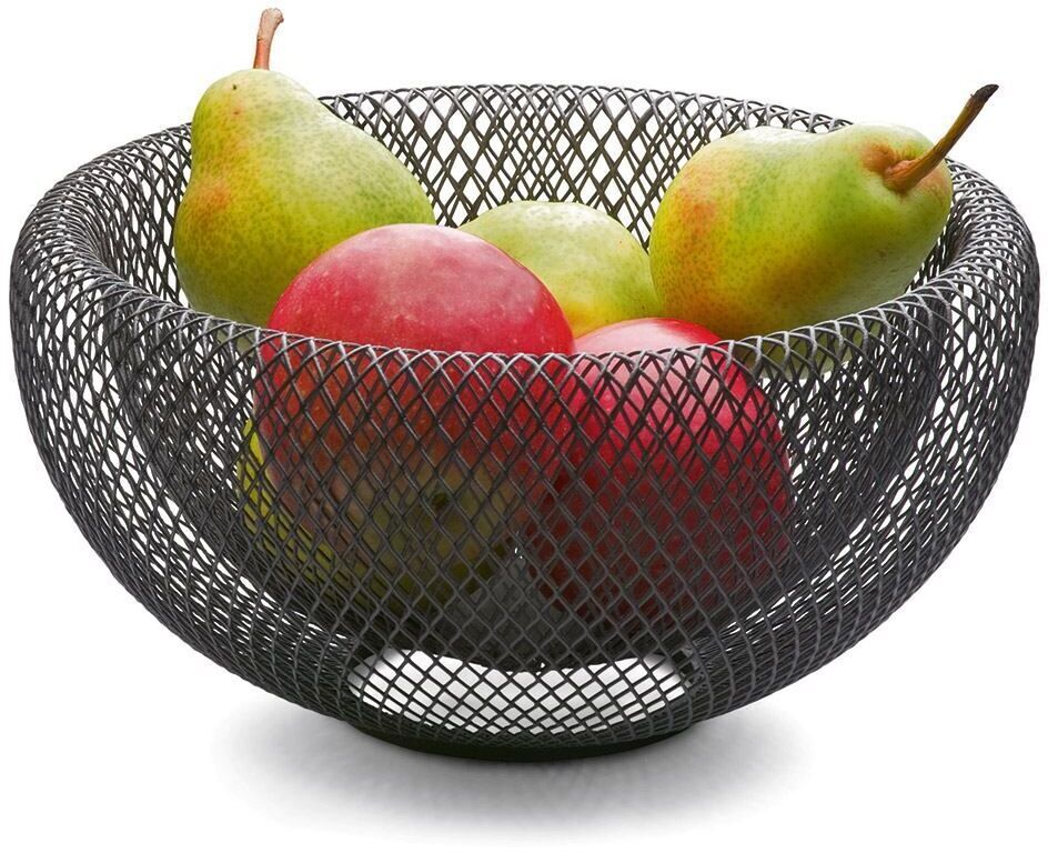 Eine Schale im Mesh-Design aus schwarzem Drahtgeflecht mit grünen und roten Früchten darin, auf einer weißen Oberfläche stehend.