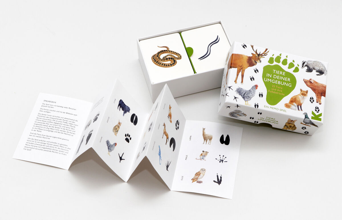 Memo-Spiel »Tiere in deiner Umgebung - 25 Tiere und ihre Fußabdrücke«. Das Spiel zeigt verschiedene Tiere und ihre Fußabdrücke auf illustrierten Karten. Die Verpackung und die Spielkarten sind grün, weiß, braun, schwarz, und grau. Ein aufklappbares Heft ist ebenfalls enthalten, das weitere Informationen zu den Tieren und ihren Spuren bietet.