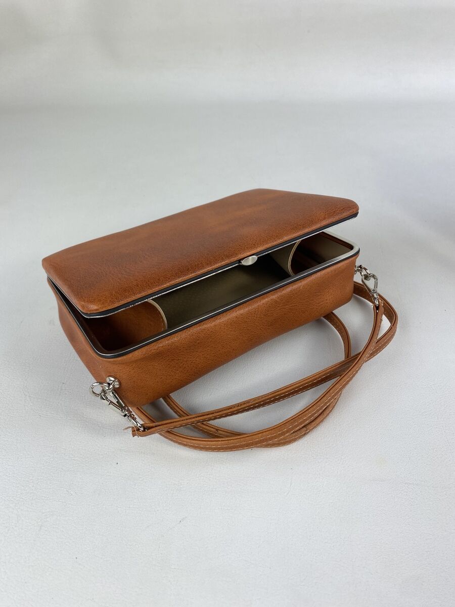 Kleine, elegante Damen-Handtasche aus cognacfarbenem Leder mit silbernen Details und schlichten Verschluss. Geeignet für verschiedene Anlässe und Alltagsgebrauch.