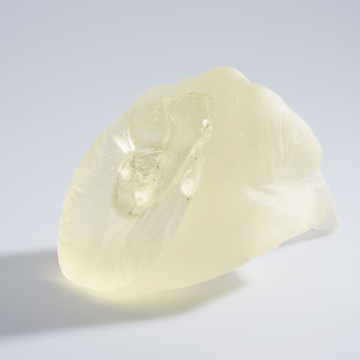 Eine Skulptur aus transparentem Glas, die ein abstrahiertes Design zeigt, erstellt von Ai Weiwei. Die Oberfläche ist glatt und glänzend, in cremefarbenen Tönen gehalten.