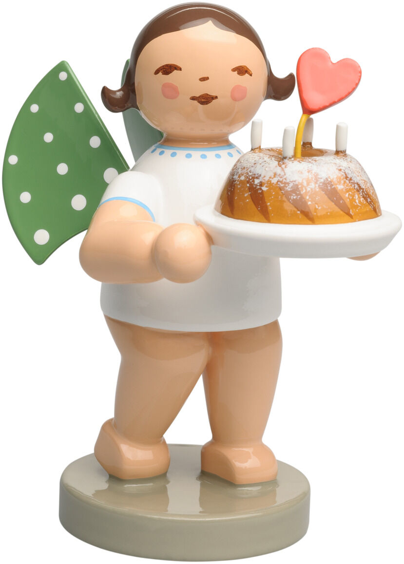 Holzfigur »Engel mit Kuchen und Herz« von Wendt & Kühn: Ein rundlicher Engel in weißem Kleid mit blauem Punktbesatz steht auf grauem Rundsockel. Grüne Flügel mit weißen Punkten ragen seitlich hervor. Er trägt einen glasierten Gugelhupf auf weißem Teller; darauf stecken zwei Kerzen und ein rosa Herz.