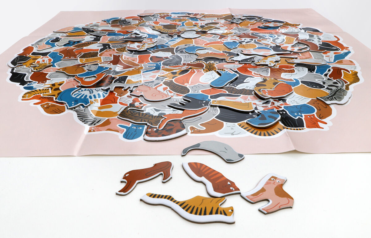 Das Bild zeigt ein 299-teiliges Katzenpuzzle mit verschiedenen farbigen Katzenformen auf einem weißen Untergrund.