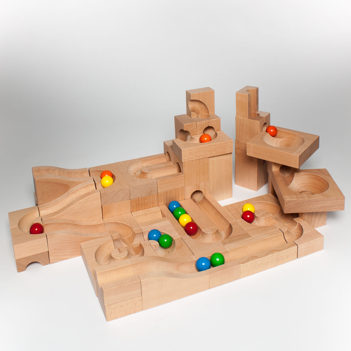 Eine Kugelbahn aus Holz mit verschiedenen bunten Kugeln auf einer wellenförmigen Strecke. Die Kugelbahn besteht aus modularen Holzblöcken und ist in Naturholzfarbe gehalten.
