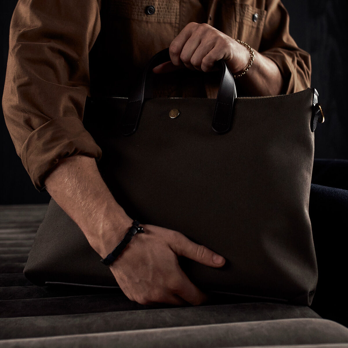 Person hält eine stilvolle, schwarze Laptop-Tasche mit Ledergriffen in der Hand, die aus hochwertigem Material gefertigt ist. Perfekt für Business-Anlässe und den täglichen Berufsalltag.