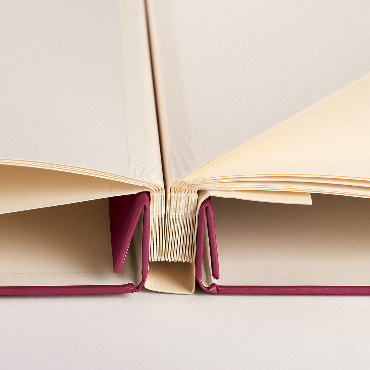 Ein offenes Fotoalbum mit weiß-beigen Seiten und einem rosa Cover. Perfekt zum Festhalten von Erinnerungen und zum Präsentieren von Fotos.