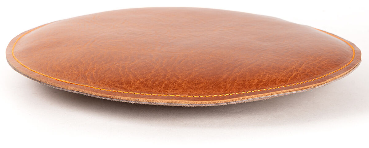 Rundes Sitzpolster in edlem Cognac-Ton, aus hochwertigem Leder gefertigt. Das schlichte, minimalistische Kissen liegt auf einer weißen Fläche und hat eine sichtbar fein genähte Umrandung. Es wirkt weich gepolstert und elegant, ideal für Sitzkomfort.