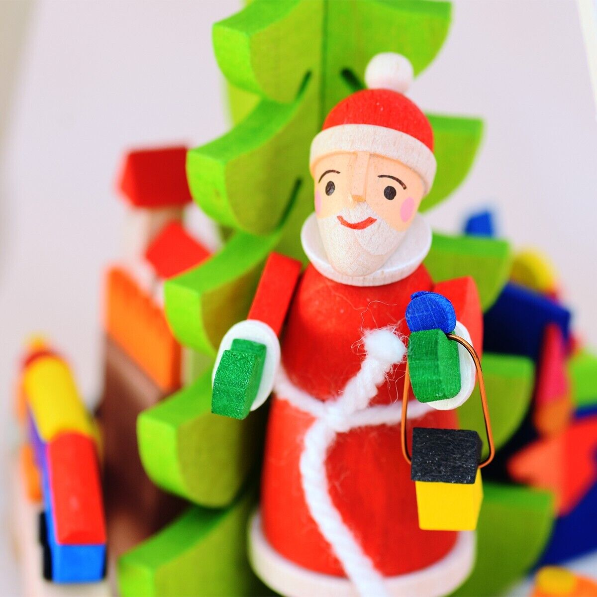 Eine bunte Teelichtpyramide mit einem Weihnachtsmann, umgeben von einem grünen Christbaum und farbenfrohen Holzbausteinen. Perfekt als Weihnachtsdekoration oder Geschenkidee für die Adventszeit.