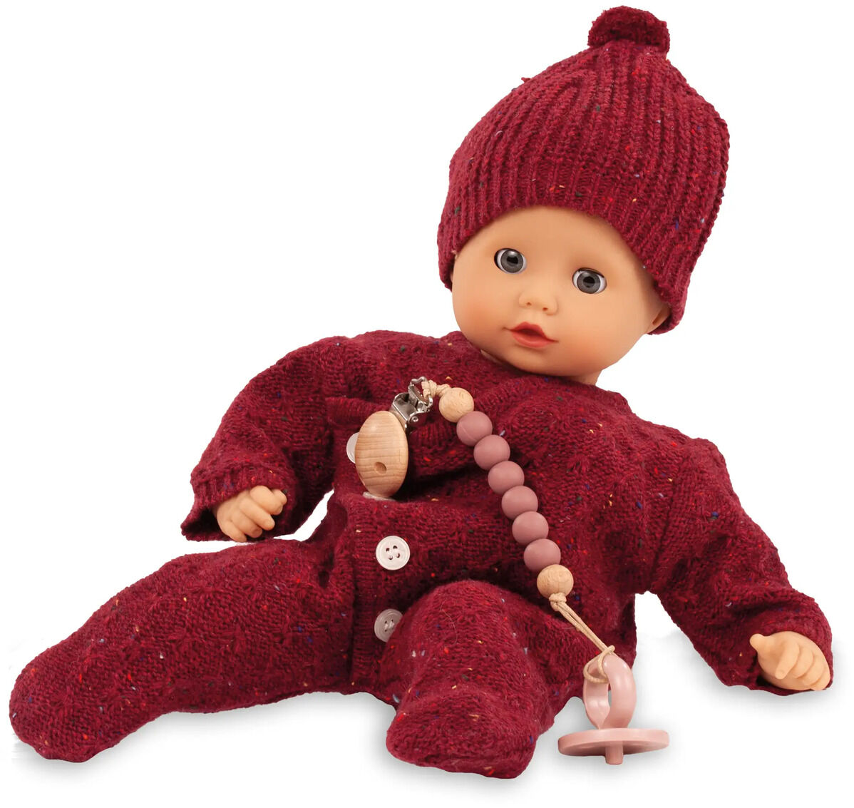 Sitzende Babypuppe Muffin Baby Jubilee mit gestricktem bordeauxrotem Strampler, passender Mütze und Schnuller; Puppe mit freundlichem Gesichtsausdruck, geeignet als Spielzeug und Geschenk für kleine Kinder.