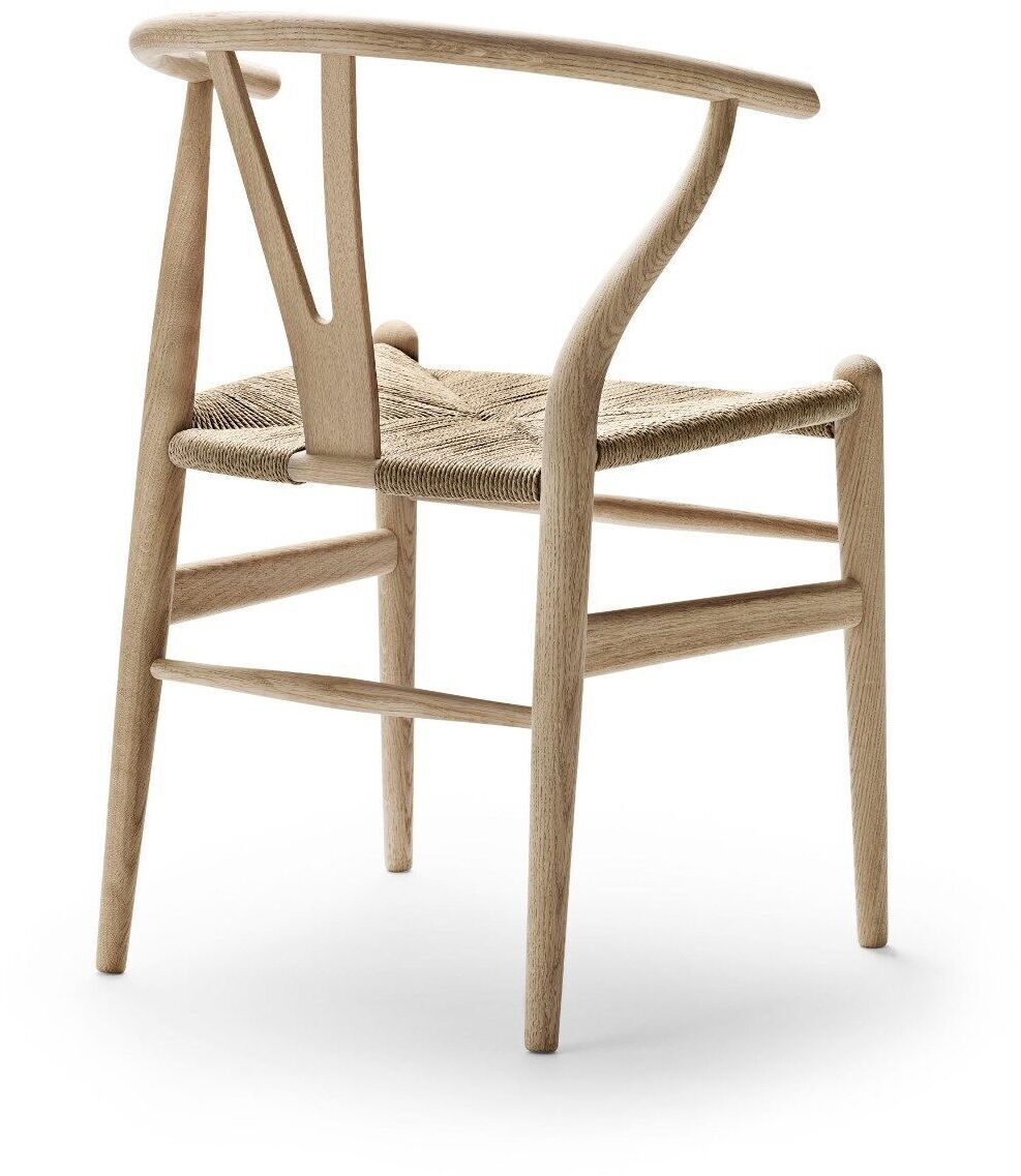 Das Bild zeigt einen „Wishbone Chair“ oder „CH24“ Stuhl von Carl Hansen & Søn. Der Stuhl besteht aus hellem Naturholz und hat eine beige, geflochtene Sitzfläche. Das Design ist schlicht und elegant mit einem skandinavischen, minimalistischen Charme.