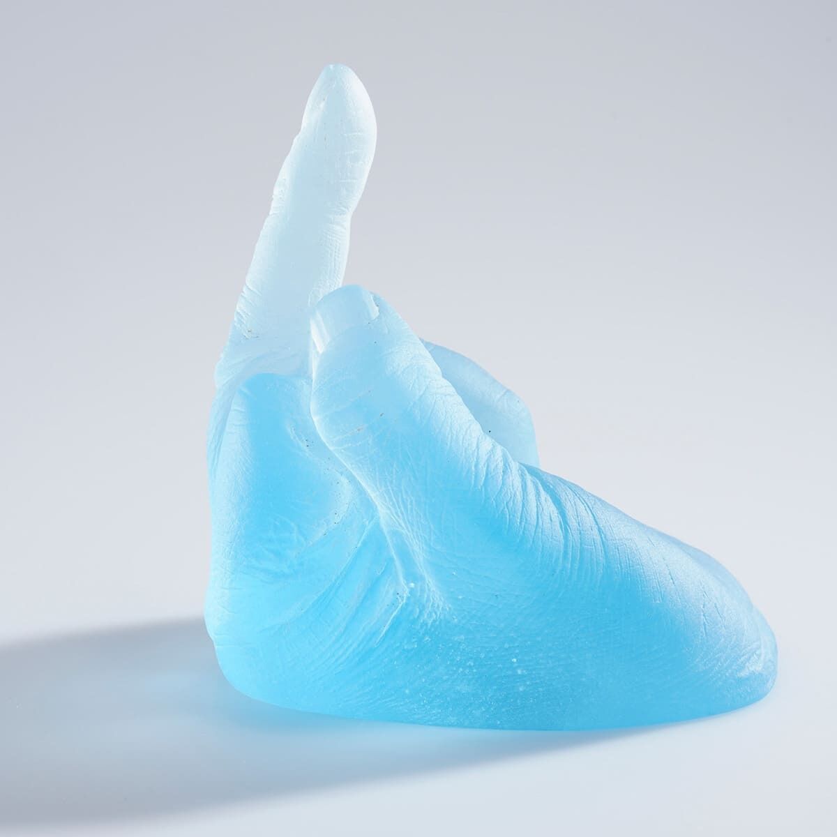 Eine gläserne Skulptur in Form einer Hand in einem hellen blauen Farbton auf einem weißen Hintergrund. Das Kunstwerk trägt den Titel »Study of Perspective in Glass« von Ai Weiwei.
