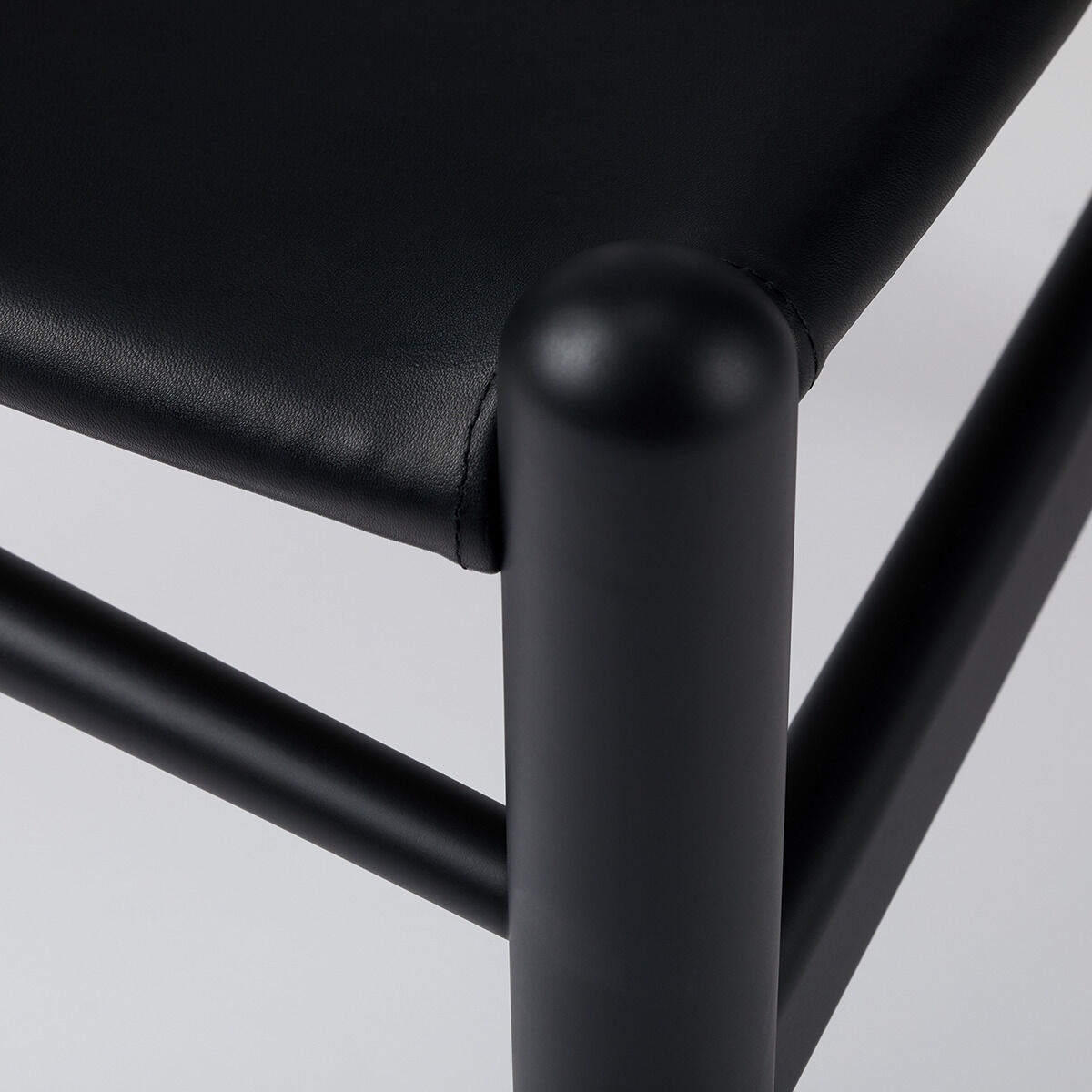 Eine stilvolle Sonderedition des Wishbone Chair aus Buche und Leder, bekannt als CH24, präsentiert sich in elegantem Schwarz. Ideal für Designliebhaber und Innenarchitekturenthusiasten.