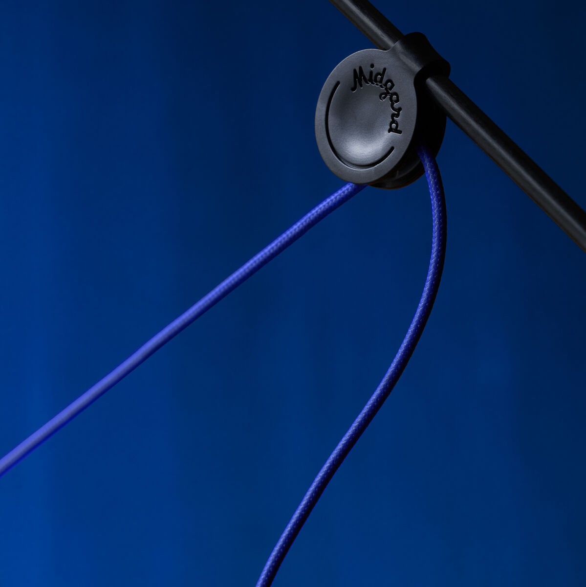 Detailansicht der ZEIT Sonderedition Stehlampe »AYNO« in Schwarz und Ultramarinblau mit elegantem, minimalistischen Kabeldesign vor blauem Hintergrund.