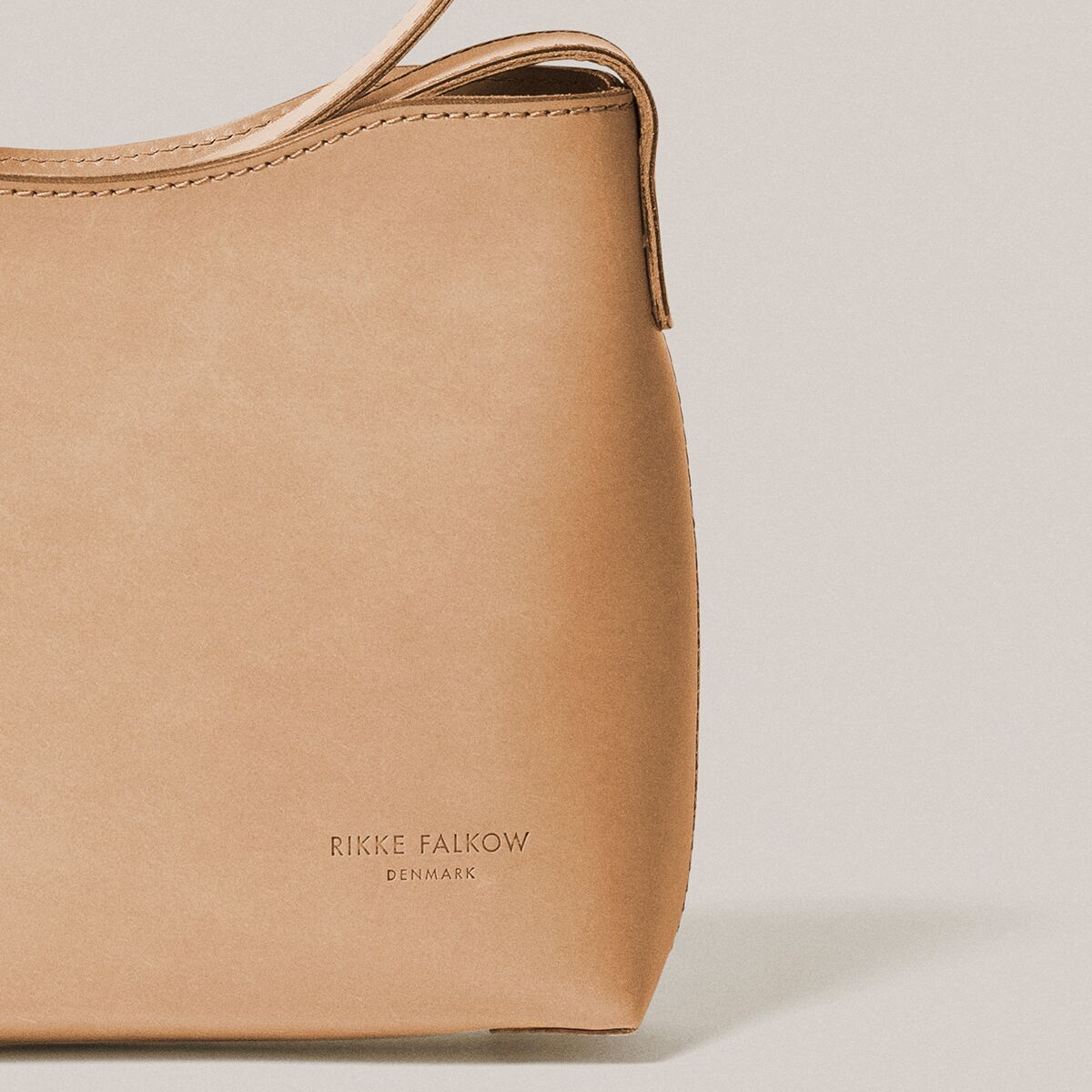 Naturfarbene Schultertasche aus pflanzlich gegerbtem Vacchetta-Rindleder, rechteckig mit weichen Konturen, glatter Oberfläche und dezenter Prägung am unteren Rand. Sichtbar sind feine Nähte, ein eleganter Schulterriemen und ein minimalistisches Design, edel und zeitlos.