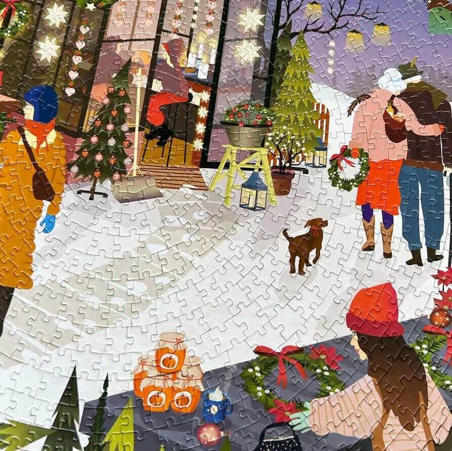 Das Puzzle zeigt einen belebten Weihnachtsmarkt in einer schneebedeckten Landschaft bei Nacht. Menschen in warmen Winterkleidung gehen zwischen festlich geschmückten Marktständen umher. Es gibt Weihnachtsbäume, Lichterketten und viele bunte Dekorationen. Ein Paar geht Arm in Arm, es gibt Kinder, die sich freuen, und ein kleiner Hund ist ebenfalls zu sehen. Der Himmel ist dunkel und mit Sternen bedeckt, mit einem leuchtenden Mond darüber.