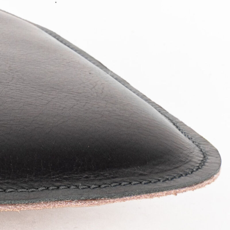 Detailaufnahme eines eckigen Sitzpolsters aus schwarzem, pflanzlich gegerbtem Rindleder mit sichtbarer Naht und Wollfilz-Rückseite; modernes, edles Wohnaccessoire von Harold's Lederwaren, ideal für Stühle oder Bänke.