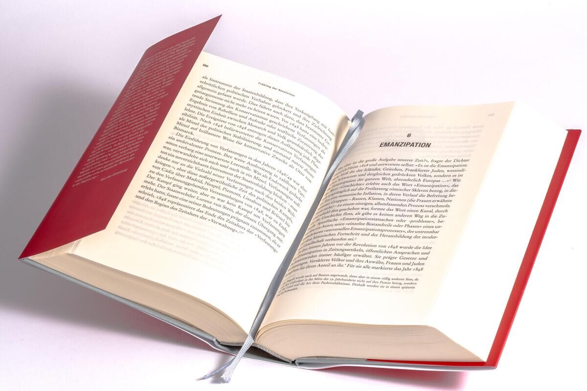 Ein aufgeschlagenes Buch mit rotem Einband und grauem Lesezeichen. Es ist ein Sachbuch mit dem Titel 'Clark, C: Frühling der Revolution'.