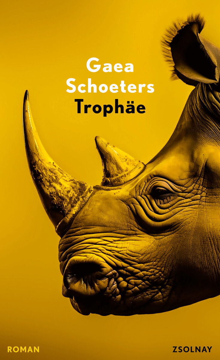 Das Cover des Buches 'Trophäe' von Gaea Schoeters zeigt ein Nahaufnahmeporträt eines Nashorns vor einem gelben Hintergrund. Oben sind die Wörter 'Gaea Schoeters Trophäe' in weißer Schrift zu sehen. Unten rechts ist der Name 'Zsolnay' als Verleger abgedruckt.