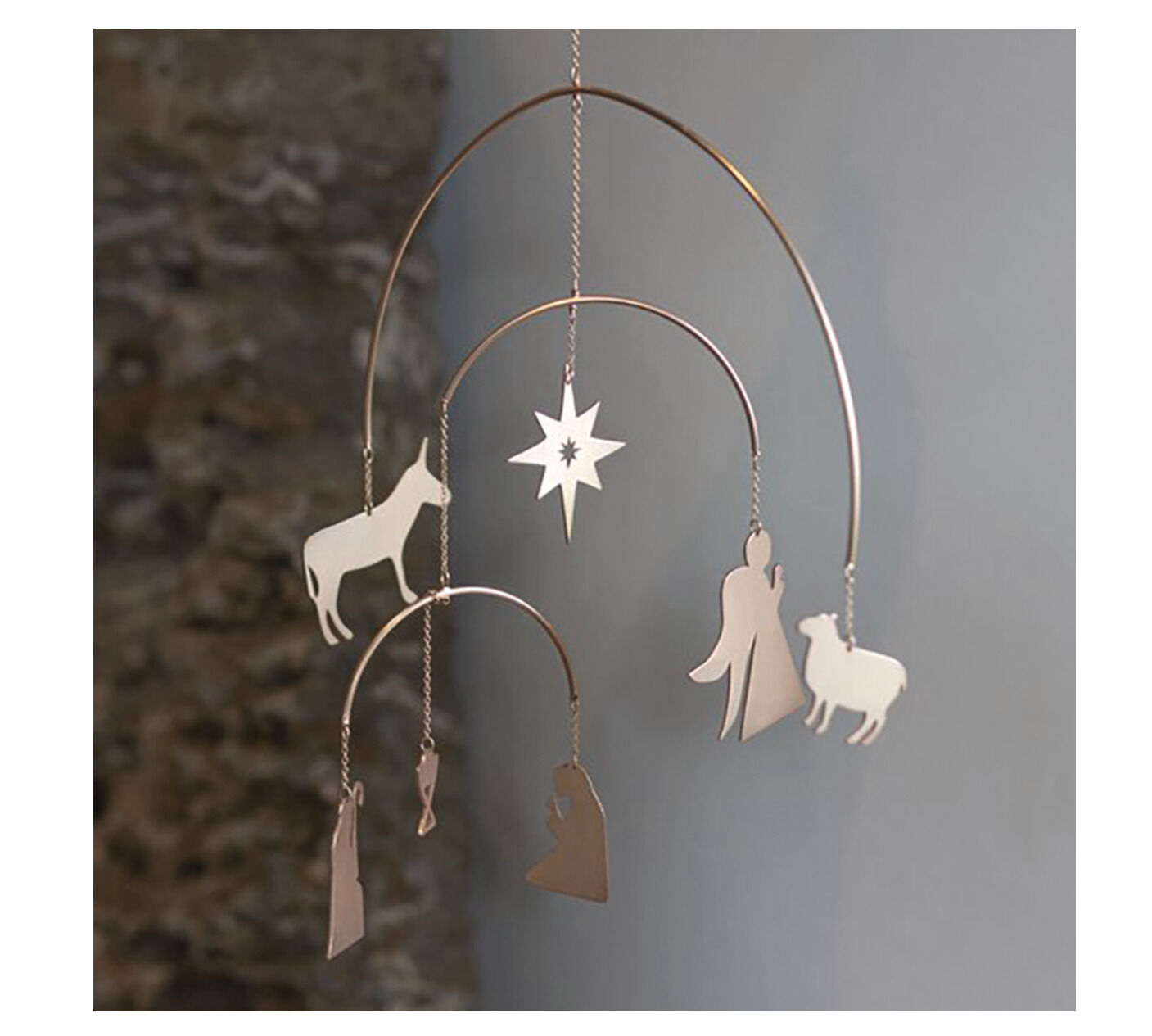 Mobiles Kunstobjekt aus silberfarbenem Metall mit weihnachtlichen Motiven, darunter Engel, Heilige Familie, Schafe, Esel und ein Stern. Das Mobile hängt frei im Raum und eignet sich als minimalistische Weihnachtsdekoration.