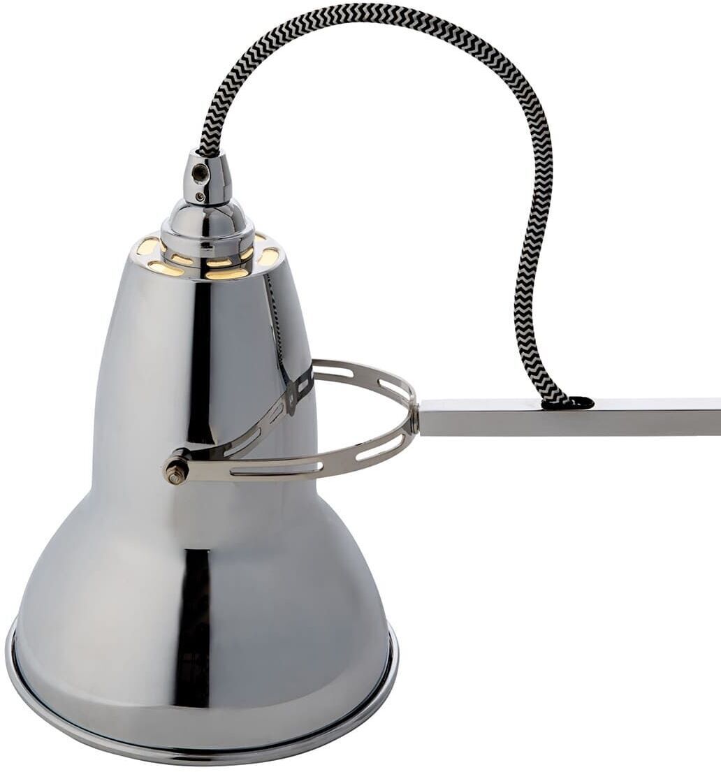 Die Tischleuchte »Anglepoise Original 1227 Brass Desk Lamp« zeigt eine elegante Messing-Schreibtischlampe mit einem verstellbaren Arm und einem klassischen, industriellen Design. Sie hat eine silberfarbene Oberfläche mit einem schwarz-weiß gemusterten Kabel.