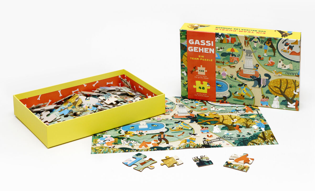 Puzzle »Gassi gehen« zeigt eine bunte Landschaft mit Menschen und Hunden auf Spaziergang, umgeben von Bäumen, Teichen und verschiedenen Outdoor-Szenen. Enthält eine Schachtel und verschiedene Puzzle-Teile.