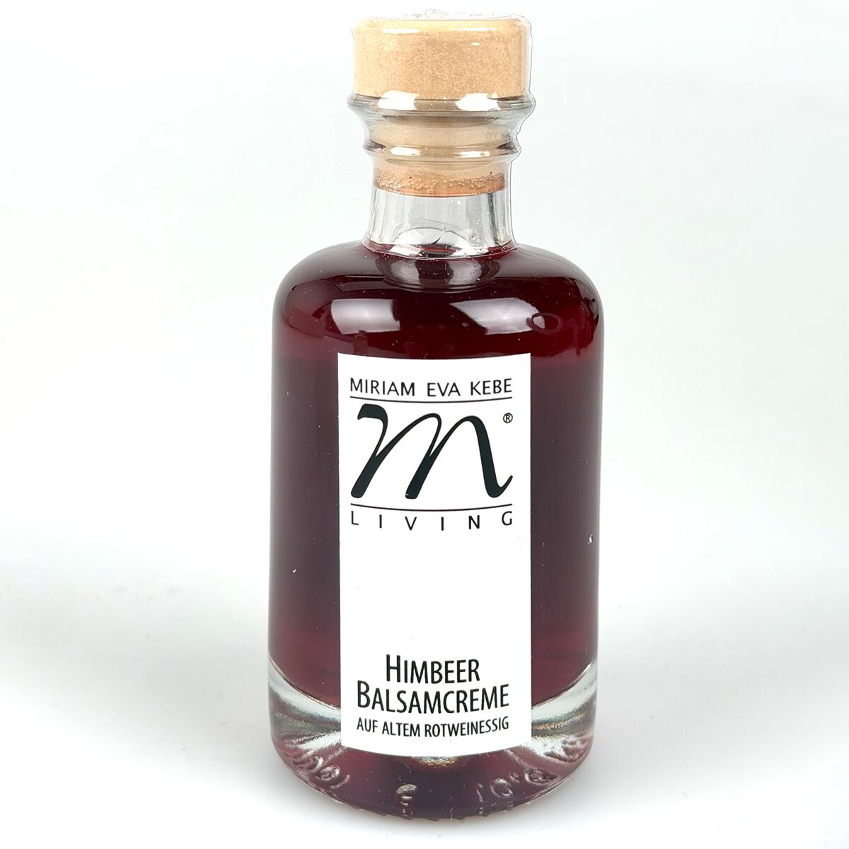 Eine Flasche mit dunkelroter Flüssigkeit, beschriftet als 'Himbeer Balsamcreme auf altem Rotweinessig' von Kebe. Die Glasflasche trägt ein weißes, rechteckiges Etikett mit schwarzer Aufschrift und einem goldfarbenen Verschluss. Das Produkt wirkt edel und hochwertig.