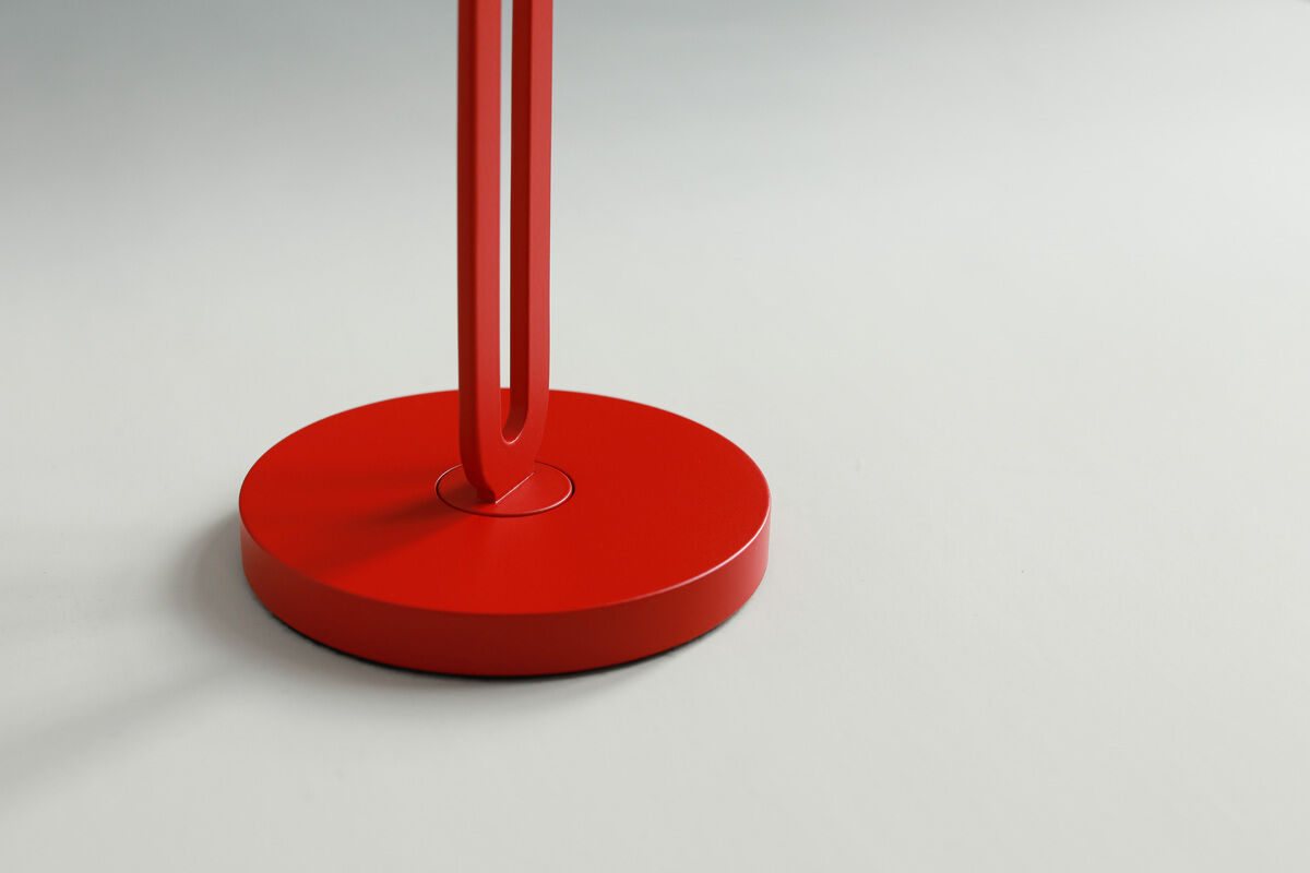 Abgebildet ist die Basis einer Tischlampe namens »Echo« in schlichter, moderner Form. Die Lampe ist in einem auffälligen Rotton gehalten mit einem runden Standfuß auf einem hellen Hintergrund.