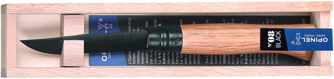 Taschenmesser »No 08 BLACK OAK« von Opinel, präsentiert in einer Holzkiste. Das Messer hat einen Holzgriff aus Eichenholz und eine schwarze Edelstahlklinge. Es liegt auf einer blauen Beschreibungskarte.