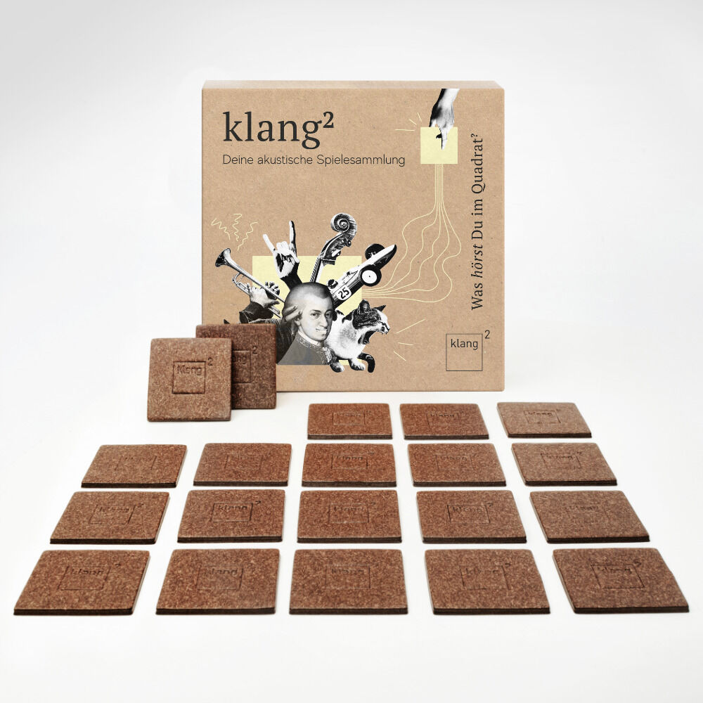 Das Bild zeigt die „klang² Spielesammlung Buchbinder Edition“, bestehend aus 18 quadratischen Holzplättchen, die in drei Reihen zu je sechs Plättchen angeordnet sind. Das Verpackungsdesign ist in beige Tönen gehalten und mit Illustrationen sowie dem Schriftzug „klang²“ und „Spielesammlung“ bedruckt.