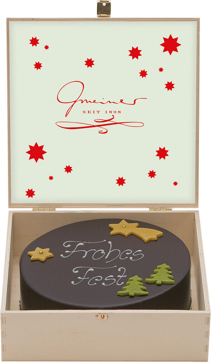 Eine festliche Torte, dekoriert mit essbaren Sternen und Tannenbäumen, befindet sich in einer Holzkiste mit einem Schriftzug 'Frohes Fest'. Die Kiste ist innen mit rotem Text und kleinen roten Sternen verziert.