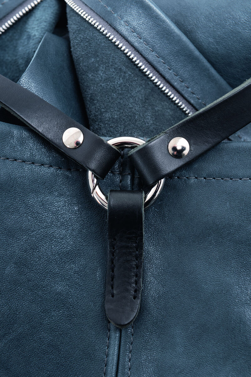 Nahaufnahme einer blauen Ledertasche namens »Nabuko« mit silbernen Metallverzierungen und schwarzen Lederakzenten.
