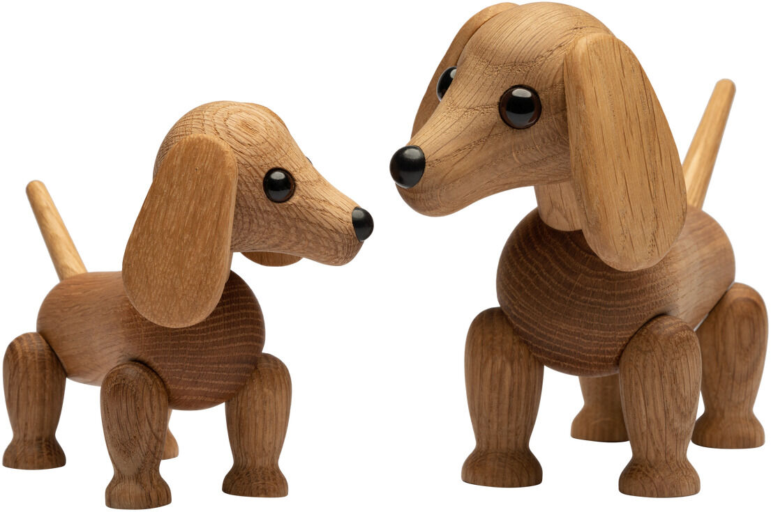 Zwei detaillierte Holzfiguren in Form von Dackeln der Serie »Dackel Amigo« von Spring Copenhagen stehen auf weißem Hintergrund. Die Figuren sind naturbelassen, zeigen schöne Holzmaserungen und haben große schwarze Augen sowie bewegliche Beine und Schwänze.