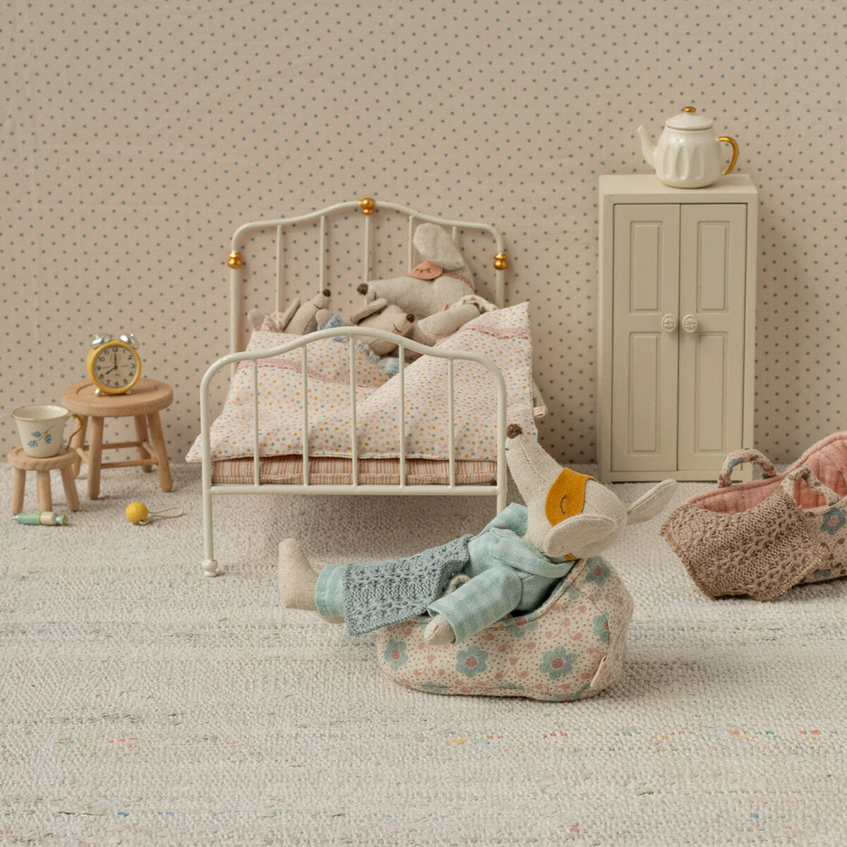 Zwei Stoffmäuse als Mama und Papa liegen in einem Miniaturbett in einer liebevoll gestalteten Puppenzimmerszene, mit weiteren kleinen Möbelstücken und Accessoires in sanften Pastellfarben. Das Bild zeigt detailreiche Miniaturen und Zubehör für Rollenspiel und Dekoration im Kinderzimmer.