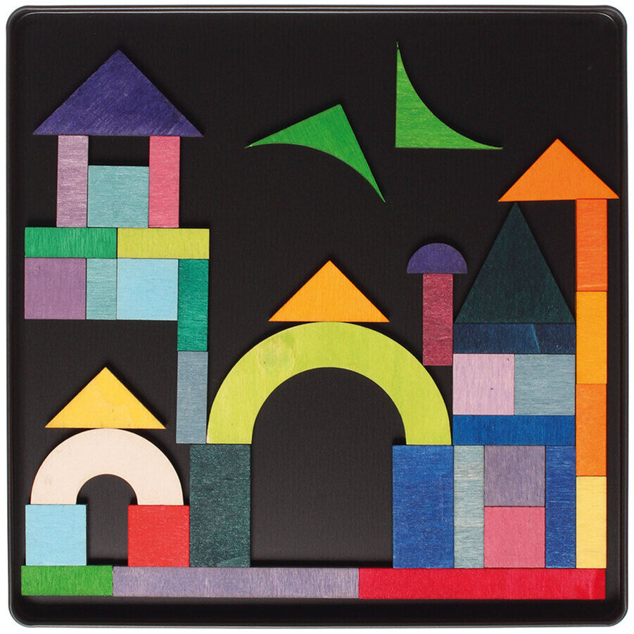 Ein Magnetspiel namens 'Geo-Grafisch' zeigt bunte geometrische Holzteile, die auf einem schwarzen Hintergrund eine Stadtlandschaft bilden. Das Spiel fördert Kreativität und Geschicklichkeit bei Kindern.