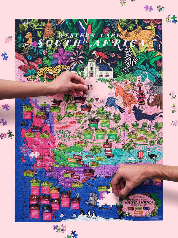 Zwei Personen setzen ein farbenfrohes Puzzle zusammen, das eine Karte von Südafrika mit verschiedenen Weinanbaugebieten und Tieren zeigt.