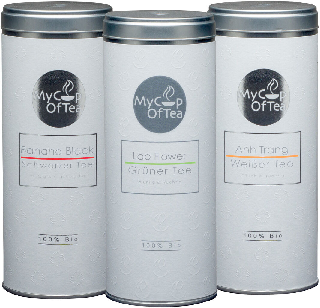 Ein Tee-Set mit der Aufschrift ‚‚My Cup of Tea‘‘ bestehend aus drei zylindrischen Dosen. Die Dosen sind weiß und jeweils beschriftet mit ‚‚Banana Black‘‘, ‚‚Lao Flower‘‘ und ‚‚Anh Trang‘‘.