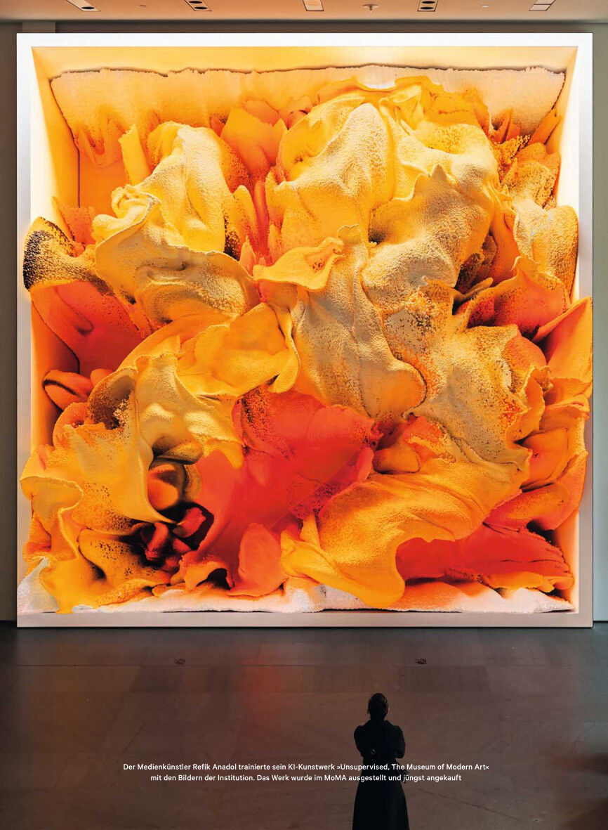 Eine große, moderne Kunstinstallation in dominierenden Gelb- und Orangetönen, die weiche, fließende Formen zeigt und in einem hell erleuchteten Raum ausgestellt ist. Im Vordergrund steht eine Person, die das Kunstwerk betrachtet.