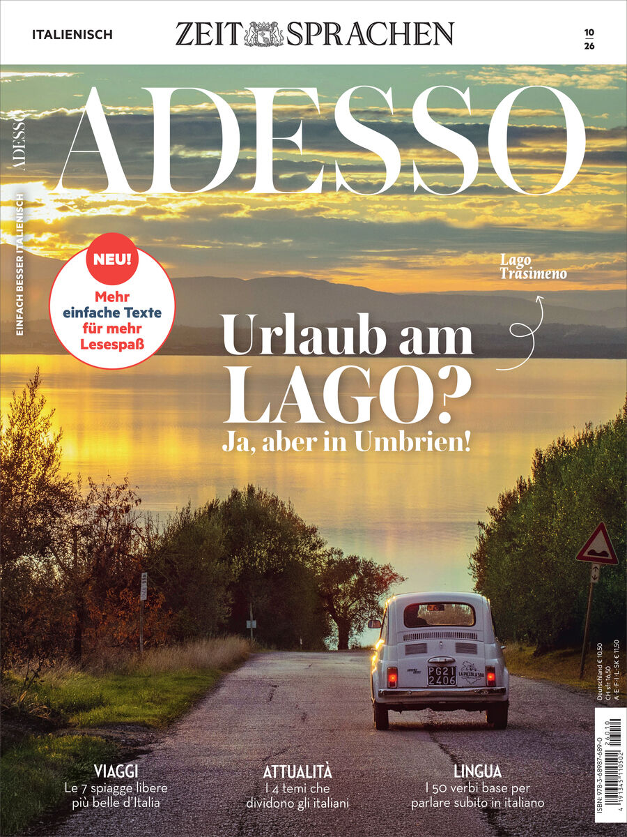 Cover des Adesso Magazins 10/2026 von Spotlight Verlag. Im Vordergrund fährt ein weißes Auto eine Landstraße entlang, dahinter ein See (Lago Trasimeno) bei Sonnenuntergang, eingerahmt von Bäumen und hügeliger Landschaft. Überschriften und Textschwerpunkte sind deutlich erkennbar.