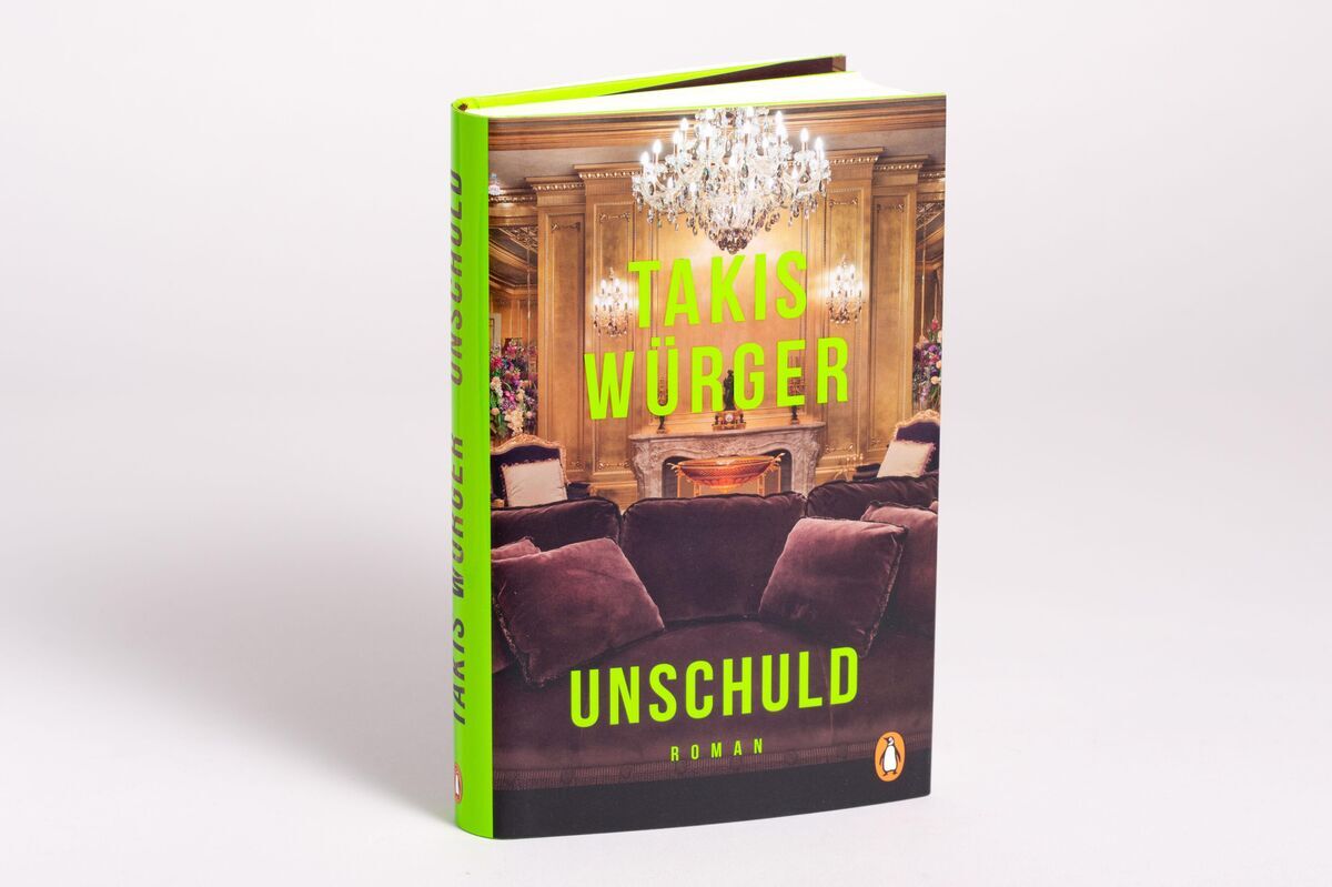 Das Buch 'Unschuld' von Takis Würger zeigt ein luxuriöses Wohnzimmer mit einem Kronleuchter auf dem Cover. Der Titel und der Autorenname sind in hellem Grün geschrieben. Im Hintergrund sind Sitzmöbel und ein Kamin zu sehen.