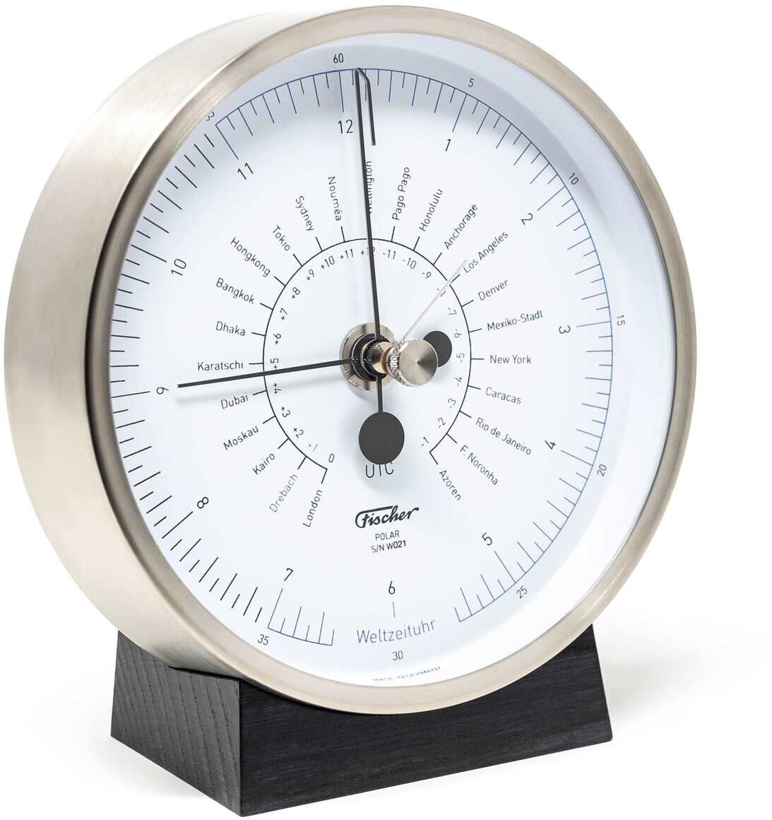 Ein elegantes und funktionales Tischuhr-Modell. Die Uhr verfügt über einen silbernen Metallrahmen und ein weißes Zifferblatt mit schwarzen Markierungen und Zeigern, die die Uhrzeit anzeigen. Es gibt Zeitangaben für verschiedene Städte weltweit und eine schwarze Basis. Ein einzigartiges Zeitmessinstrument, das sich gut als Accessoire in modernen Wohn- und Arbeitsumgebungen eignet.