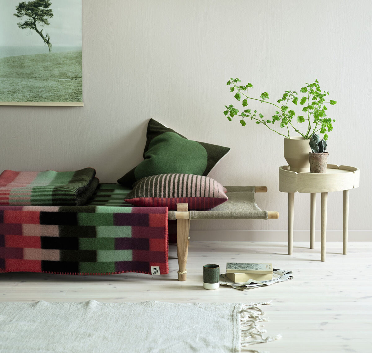 Kissen »ÅSMUND GRADIENT« auf einem Sofa im Wohnzimmer. Bunte, gestreifte Kissen in verschiedenen Farben, Grünpflanze auf einem Beistelltisch und ein Bild an der Wand im Hintergrund. Minimalistische und gemütliche Inneneinrichtung im skandinavischen Stil.